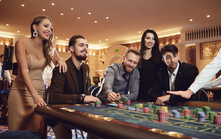 Group of stylish adults enjoying a lively casino table game while live music entertainment creates an energetic atmosphere.