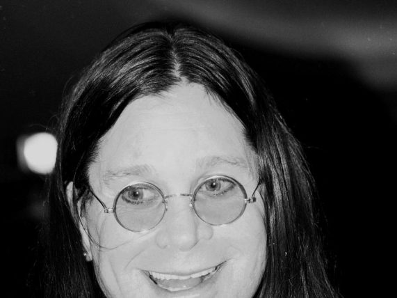 Ozzy Osbourne smiling with circular glasses on