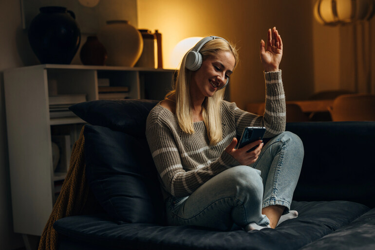 Smiling woman listening to music with headphones while going through a dating app